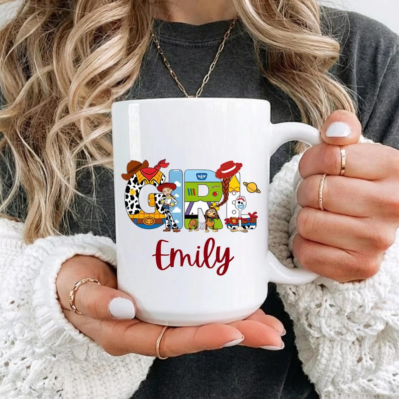 May include: White ceramic mug featuring the name "Chris" in colorful, cartoon-style letters with Toy Story character illustrations. The name "Emily" is written in red script below the main text. The mug has a large handle.