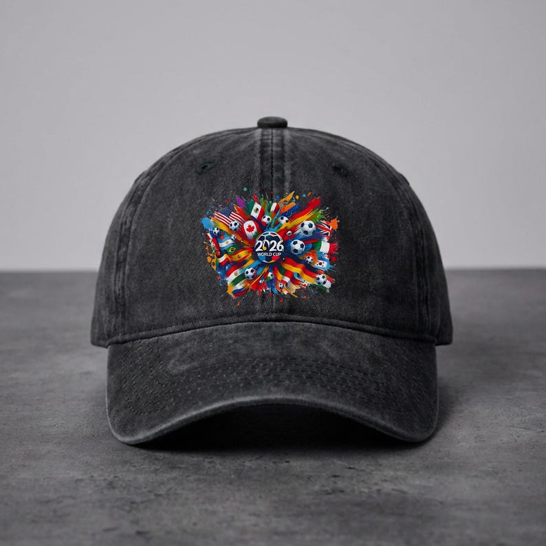 May include: A black denim baseball cap featuring a colorful graphic design with soccer balls, flags, and the text "2026 WORLD CUP". The design is centered on the front of the cap.