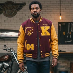 May include: A maroon and gold varsity jacket with a bear patch and the letter "K". The jacket has gold sleeves and the number "04". The person is standing in front of a motorcycle.