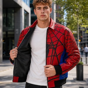 May include: A red leather jacket featuring a black spiderweb pattern, a classic collar, a front zipper closure, and black ribbed cuffs. The jacket has blue side panels and a solid black interior lining, worn over a plain white t-shirt and dark jeans.
