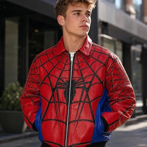 May include: A red and blue leather bomber jacket featuring a black spiderweb pattern across the chest and sleeves, a central black spider emblem, a silver front zipper, a classic collar, and black ribbed cuffs and hem at the waist.