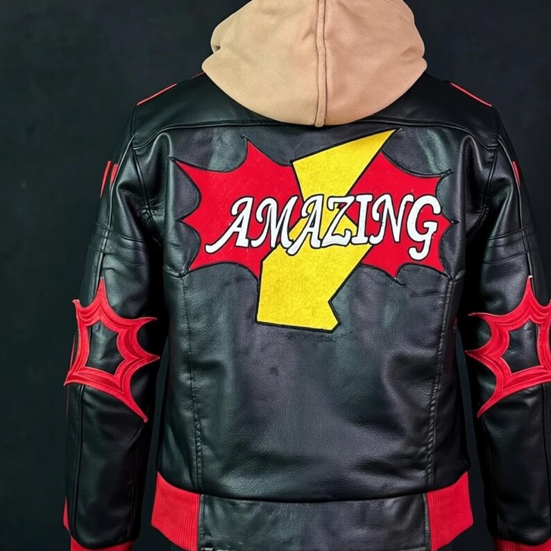 May include: A black jacket with a tan hood, featuring a large yellow lightning bolt graphic on the back with the word AMAZING in white letters, surrounded by red star-like shapes. Red accents appear on the sleeves and the bottom hem of the jacket.