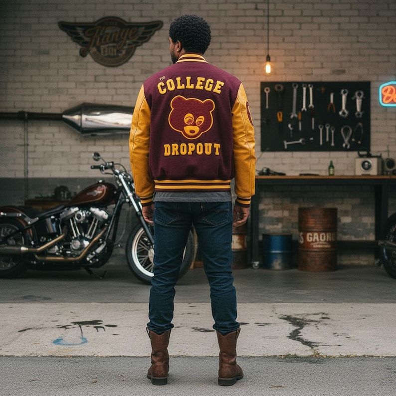 May include: A maroon and yellow varsity jacket with "THE COLLEGE DROPOUT" and a bear graphic on the back. The jacket has yellow sleeves and a striped collar and cuffs. The person is wearing blue jeans and brown boots.