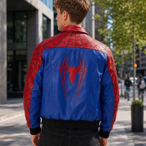 May include: A red and blue leather jacket featuring a black spiderweb pattern on the shoulders and sleeves, with a large red spider emblem centered on the back. The jacket has a classic collar, black ribbed cuffs, and a black ribbed hemline.