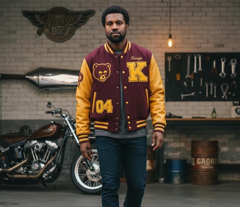 May include: A maroon and gold varsity jacket with a bear patch and the letter "K". The jacket has gold sleeves and the number "04". The person is standing in front of a motorcycle.