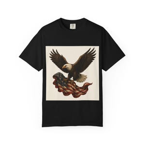 A black short-sleeved t-shirt with a graphic of a bald eagle with outstretched wings carrying a folded American flag in its talons.