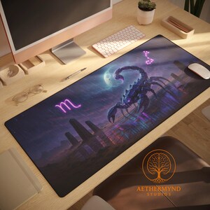 Op de afbeelding: Zwarte bureaumat met een gedetailleerde illustratie van een schorpioen onder een volle maan en een sterrenhemel. De mat bevat het sterrenbeeld Schorpioen en een sterrenbeeld. Het logo van Aethermynd Studios is zichtbaar.
