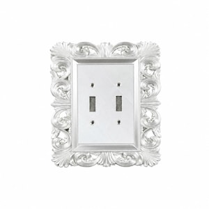 May include: A silver-colored double toggle light switch plate featuring an ornate, raised scrollwork border with intricate leaf-like patterns. The central rectangular panel is smooth and flat, containing two vertical rectangular cutouts for switches.