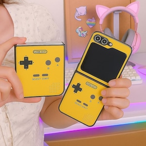 May include: Yellow phone case and a matching square-shaped case, both designed to resemble a Game Boy. Each case features a black directional pad, buttons, and the text "GAME BOY" and "SELECT START".