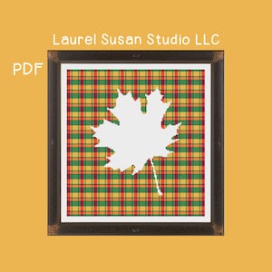May include: A white maple leaf silhouette on a red, yellow, and green plaid background. The image is framed in a dark brown frame. The text "Laurel Susan Studio LLC" is at the top of the image and "PDF" is at the bottom left.