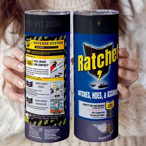 May include: Two cylindrical tumblers with black lids are held in front of a person. One features a yellow and black label with the text "DEFENSE SYSTEM" and "KILL BUGS ON CONTACT". The other has "Ratche" in yellow and a lightning bolt, with the text "BITCHES, HOES, & ASSHOLES".