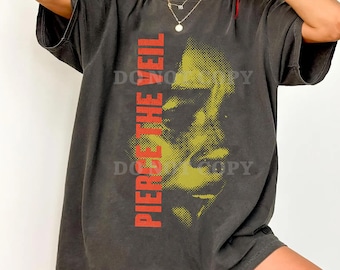 Puede incluir: Camiseta gris oscuro con el texto rojo "PIERCE THE VEIL" en el lado izquierdo. La parte delantera de la camiseta muestra una imagen en semitono amarilla y negra de una cara.