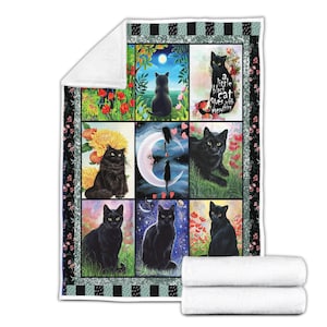 May include: A black cat-themed blanket featuring nine squares with different cat illustrations. The blanket has a black and white floral border and a white backing. One square has the text "a little black cat quees with everything".