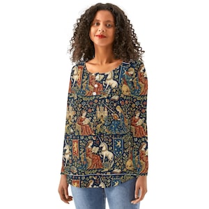 May include: A long-sleeved henley shirt featuring a dark blue tapestry-style print with repeating illustrations of unicorns, castles, and figures reading books in red, gold, and blue tones. The shirt has a round neckline with three white buttons.