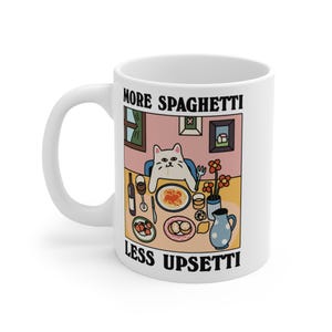 Può includere: Tazza in ceramica bianca con un'illustrazione a cartoni animati di un gatto a tavola con spaghetti e vino. Il testo sulla tazza recita "MORE SPAGHETTI LESS UPSETTI". La tazza ha un manico curvo.