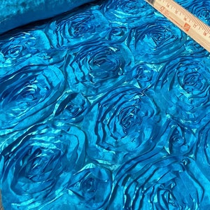 May include: Turquoise blue fabric with a 3D rose pattern. The fabric is rolled up and a measuring tape is laying on top of it. The tape reads "The Home Depot".