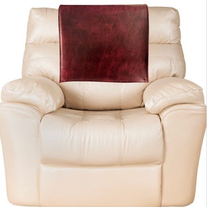 May include: A cream-colored leather recliner with a burgundy leather armrest cover.