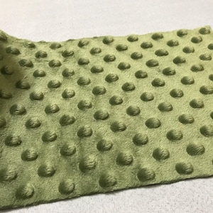 May include: A close-up of a green minky fabric with a textured dot pattern. The fabric is soft and plush.