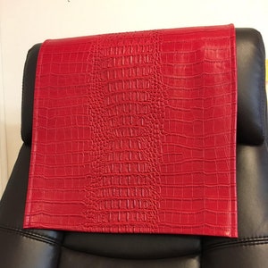 May include: Red faux leather chair headrest with a crocodile pattern.