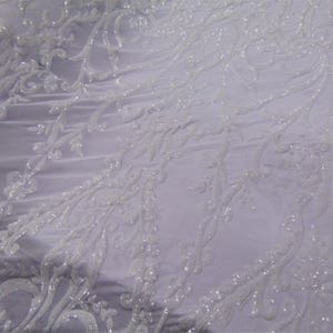 May include: White beaded lace fabric with a delicate floral pattern. The fabric is sheer and has a soft, flowing texture.
