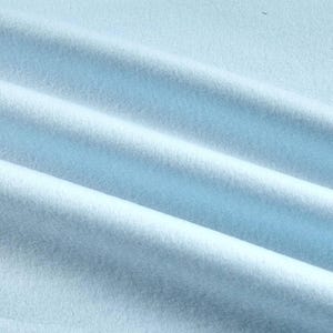 May include: Close-up of a light blue fabric with a soft, textured appearance. The fabric is folded in diagonal lines, creating a sense of depth and highlighting the material's texture. The overall effect is smooth and inviting.