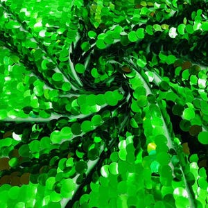 May include: A vibrant green fabric densely covered in small, round, reflective sequins. The material is arranged in a swirling, folded pattern that highlights the metallic sheen and the overlapping texture of the individual circular discs.