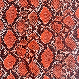 May include: Close-up of a red and brown snakeskin pattern. The pattern is made up of small, overlapping scales.