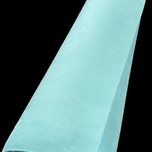May include: A roll of light mint green material with a smooth, matte texture. The cylindrical roll is positioned at an angle, showing the continuous length of the material as it spirals inward toward the center of the base of the roll.