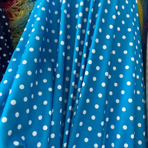 May include: A blue fabric with white polka dots. The fabric is folded and draped, showing the pattern.