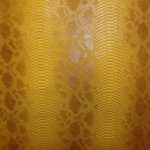May include: Close-up of a yellow snakeskin pattern. The texture features a repeating scale design with darker brown accents. The overall appearance is a vibrant, textured surface, suitable for fashion or decorative applications.