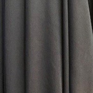 May include: A close-up of a dark gray fabric with a smooth texture. The fabric is folded and draped, creating soft folds and curves.