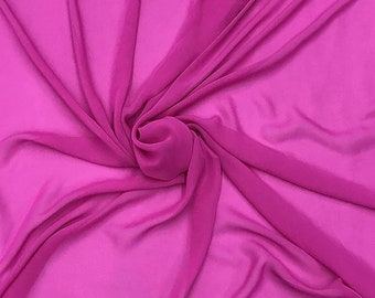 May include: A close-up of a soft, pink fabric with a smooth, silky texture. The fabric is draped and folded, creating a flowing, elegant look.