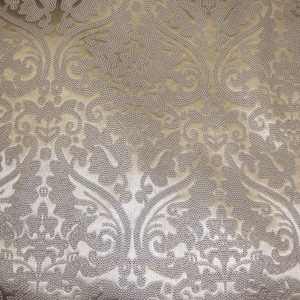 Puede incluir: Primer plano de una tela beige con un patr&oacute;n floral en relieve. La tela tiene un brillo sutil y una superficie texturizada.
