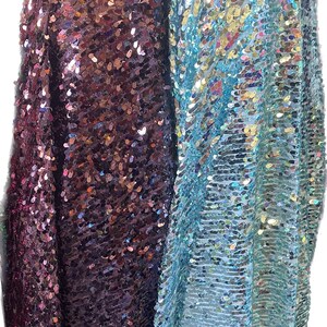 May include: Two pieces of iridescent fabric with sequins. One piece is a dark purple and the other is a light blue.
