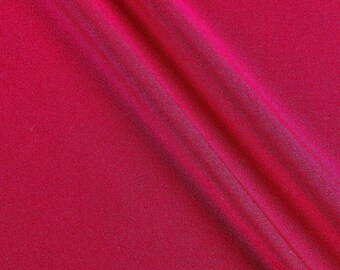 May include: A close-up of a smooth, deep red fabric with a subtle sheen. The fabric is folded in a diagonal line, creating a soft, flowing texture.