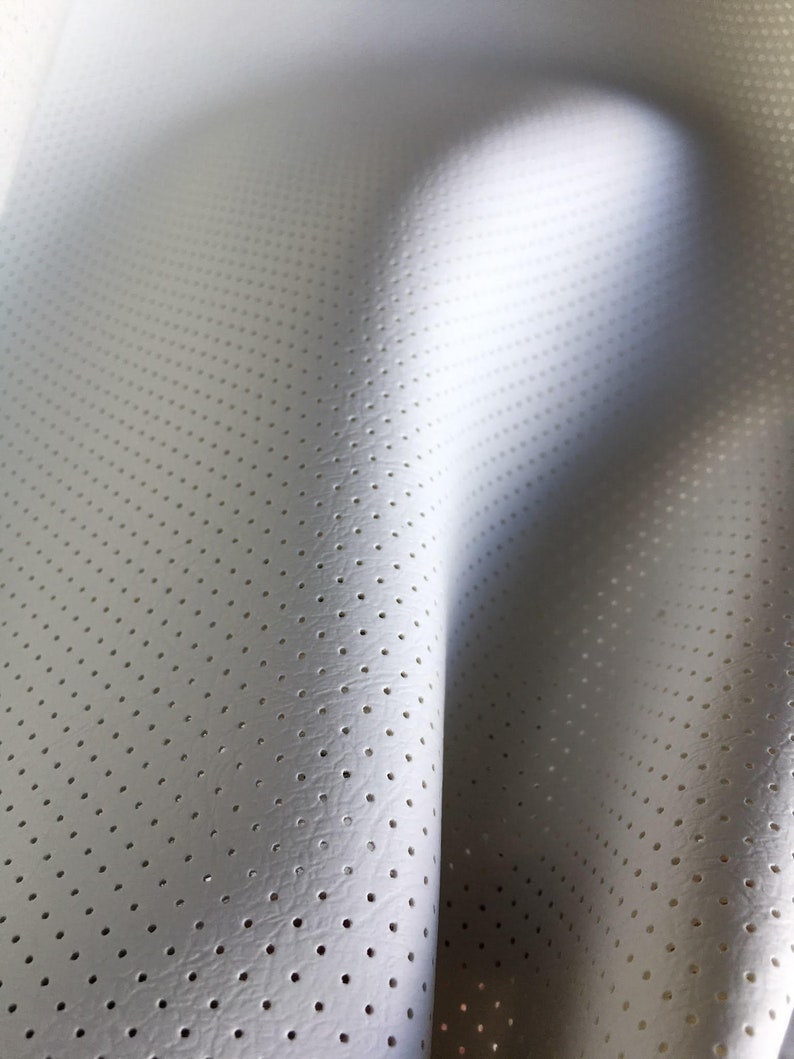 K&ouml;nnte beinhalten: Ein wei&szlig;es Material mit einem gleichm&auml;&szlig;igen Muster aus kleinen, regelm&auml;&szlig;ig angeordneten kreisf&ouml;rmigen Perforationen. Die Oberfl&auml;che weist eine feine, subtile Textur auf und ist in weichen Kurven drapiert, die Tiefe und Licht betonen.