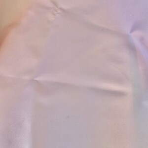 May include: A close-up of a white fabric with a subtle texture. The fabric has a slight sheen and is wrinkled in places.