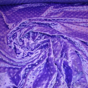 May include: Purple textured fabric with a raised dot pattern. The fabric is soft and plush.