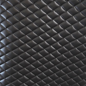 May include: Black quilted fabric with a diamond pattern. The fabric has a textured surface.
