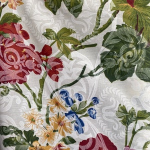 May include: White fabric with a floral pattern featuring red, pink, yellow, and blue flowers. The background has a white damask pattern.