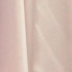 May include: A solid, light blush pink fabric with a smooth, matte texture. The material is draped to create soft, vertical folds and gentle shadows, highlighting the consistent, pale pink color and the fine, uniform weave of the textile surface.