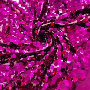 May include: A fabric material densely covered in round, reflective fuchsia pink sequins. The sequins are arranged in a swirling, spiral pattern that creates a textured, metallic surface with light-catching properties across the entire textile.
