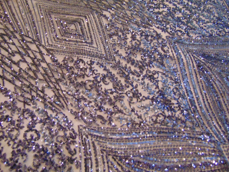 May include: A close-up of a fabric with a geometric pattern of sequins in shades of blue and purple. The sequins are arranged in a diamond pattern, creating a shimmering effect.