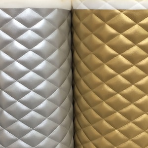 May include: Two rolls of quilted fabric, one silver and one gold. The fabric has a diamond pattern.