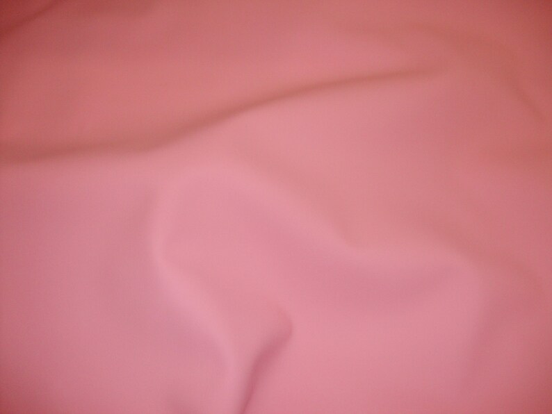 Puede incluir: Un fondo de tela lisa de color rosa s&oacute;lido con arrugas sutiles.