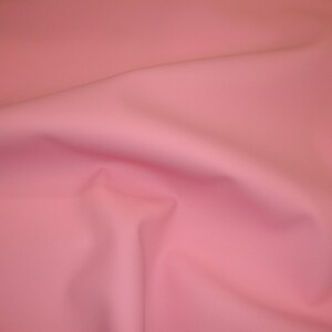 Puede incluir: Una tela lisa de color rosa p&aacute;lido con un suave y fluido drapeado.