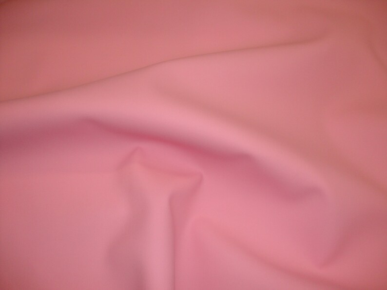 Puede incluir: Una tela lisa de color rosa p&aacute;lido con un suave y fluido drapeado.