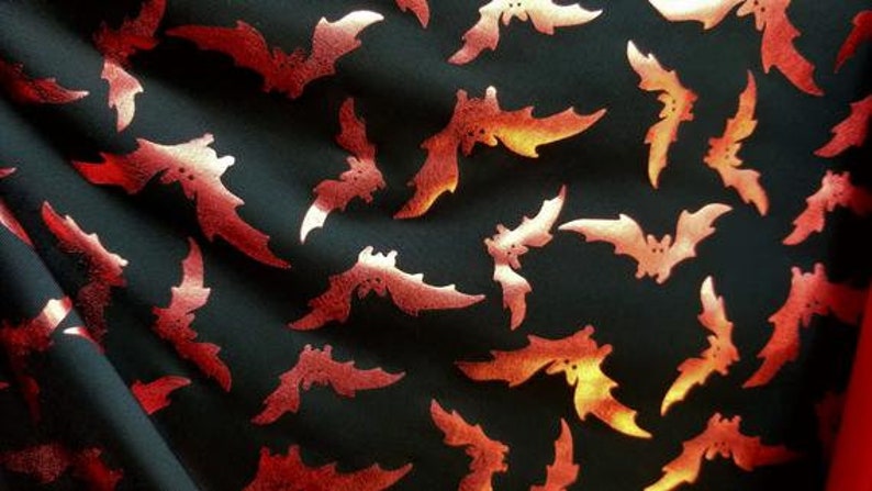 以下が含まれることがあります： 赤いコウモリが繰り返しパターンで描かれた黒い布。コウモリは光沢のあるメタリックレッドです。