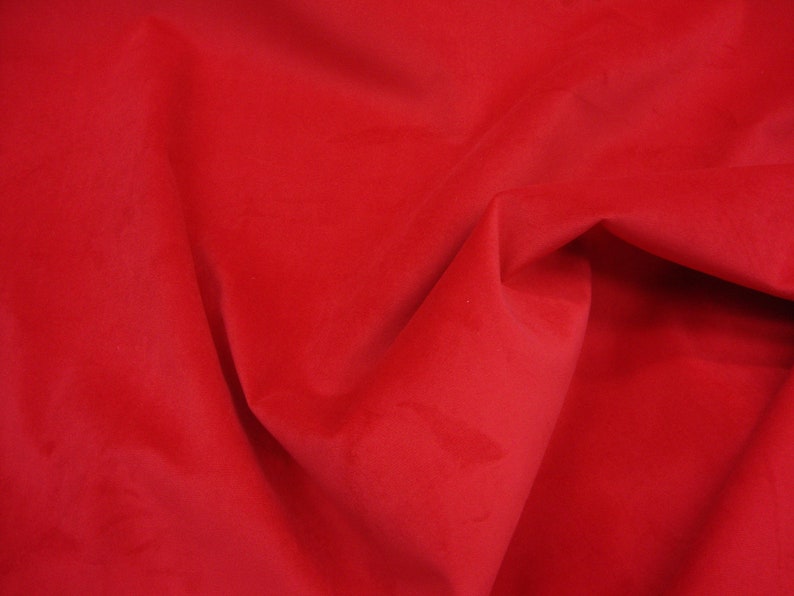 Pu&ograve; includere: Primo piano di un tessuto liscio di colore rosso con una texture morbida e vellutata. Il tessuto &egrave; piegato e drappeggiato, creando un senso di profondit&agrave; e dimensione.