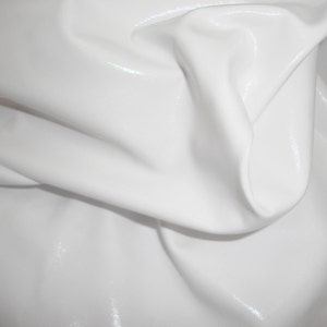 Peut inclure: Un morceau de tissu vinyle blanc avec une finition brillante et r&eacute;fl&eacute;chissante. Le mat&eacute;riau est drap&eacute; pour cr&eacute;er des plis doux et fluides ainsi que des ombres profondes, soulignant la texture lisse et la couleur blanche unie &eacute;clatante.